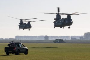 CH-47 Chinook transporthelikopters verschijnen boven het vliegveld, gadegeslagen door 'vijandelijke militairen' © Leonard van den Broek